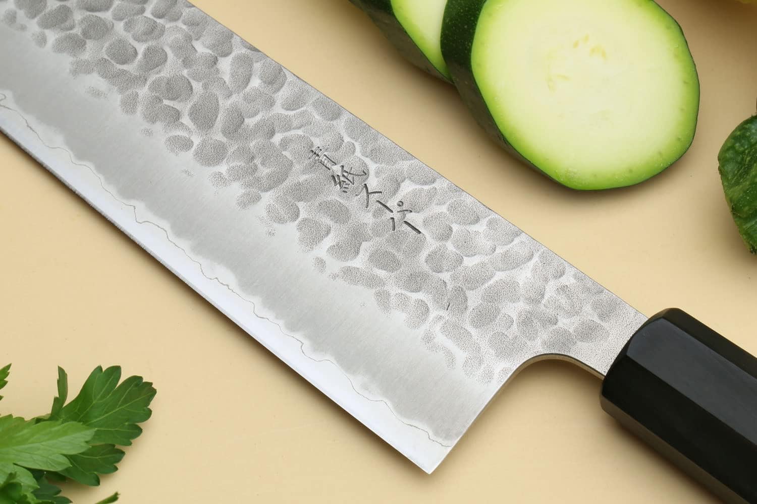 Yoshihiro Super Blue kiritsuke slicing zucchini, showing the hammered tsuchime face