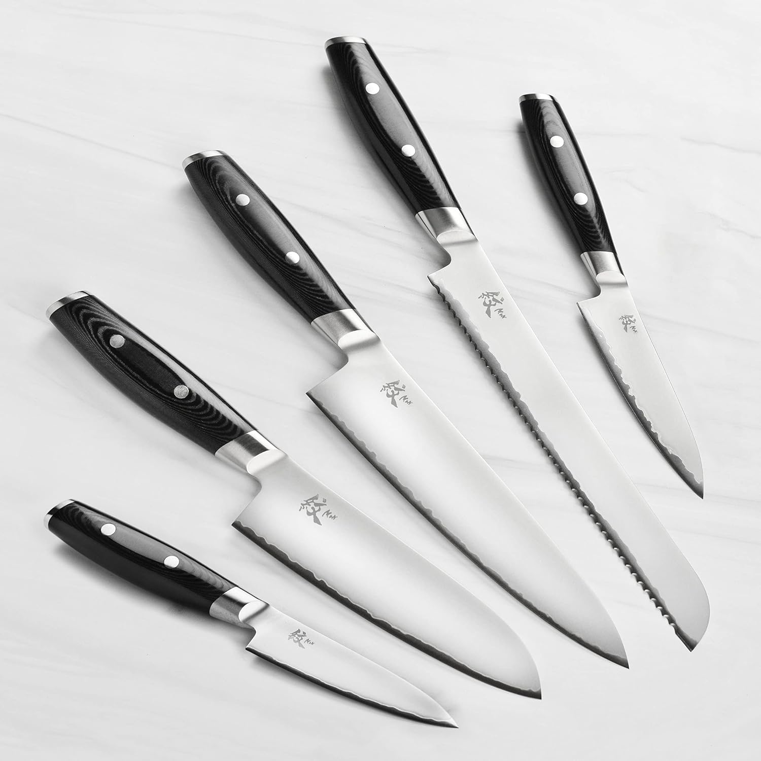 Yaxell Mon five knives laid out with black Micarta handles and satin blades