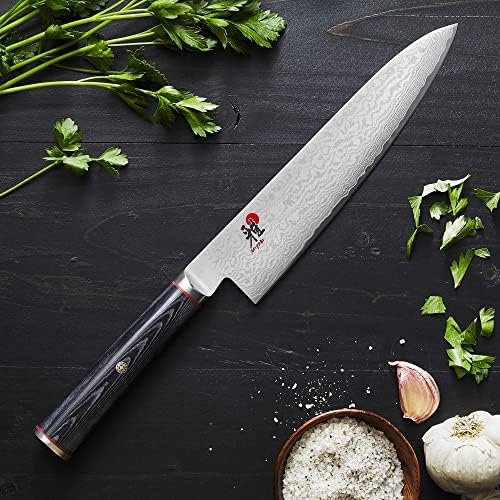 Miyabi Kaizen chef's knife styled with herbs, garlic and salt on dark wood