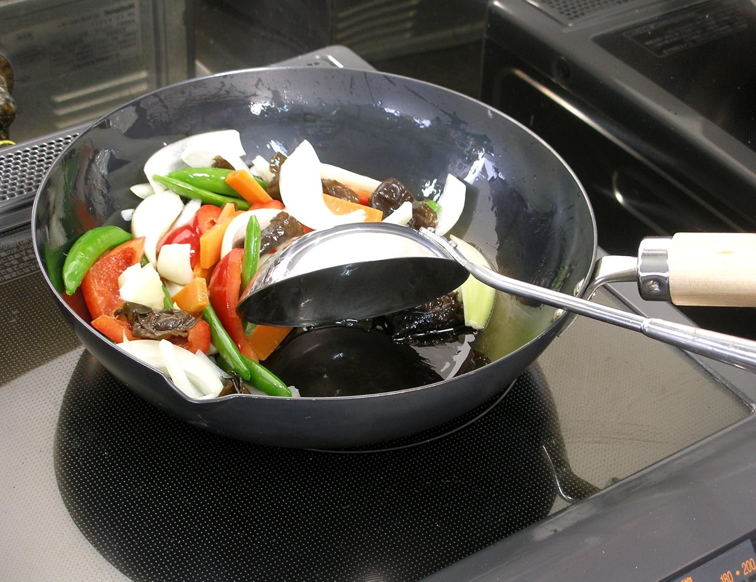Colorful vegetable stir-fry cooking in a River Light Kiwame pan on an induction hob