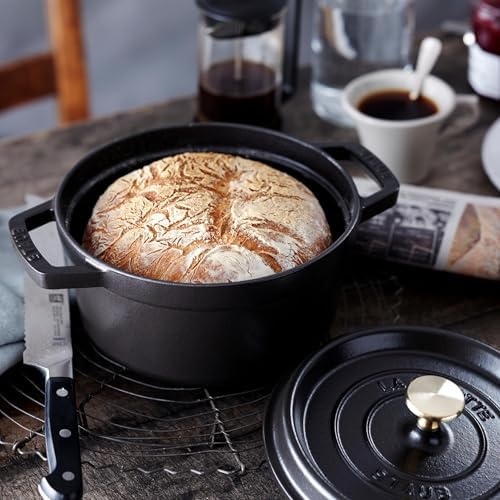 A round loaf of crusty no-knead bread baked inside a Staub Dutch oven