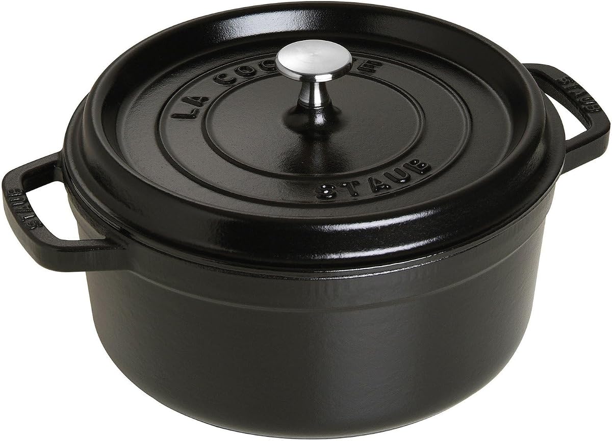 Staub matte black cast iron round cocotte with its heavy domed lid on a white background