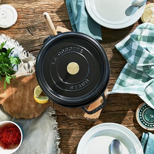Staub cocotte on a wooden table surrounded by fresh vegetables plus herbs