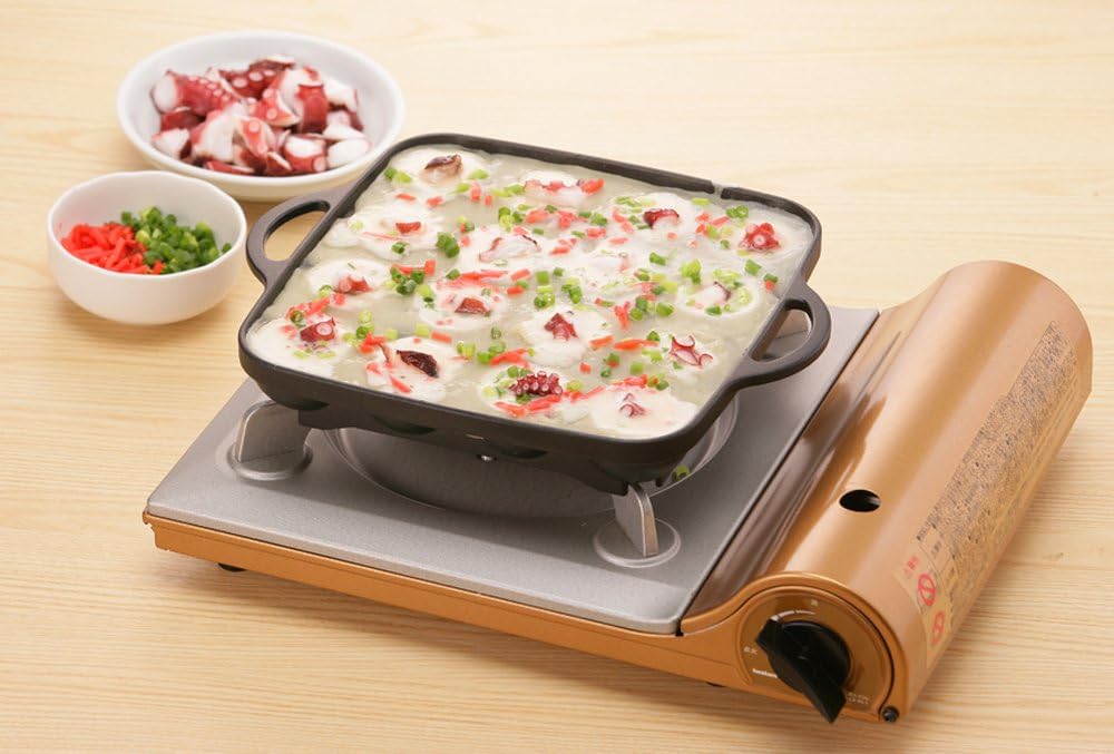 Iwatani takoyaki plate on a butane cassette stove with batter and octopus poured in