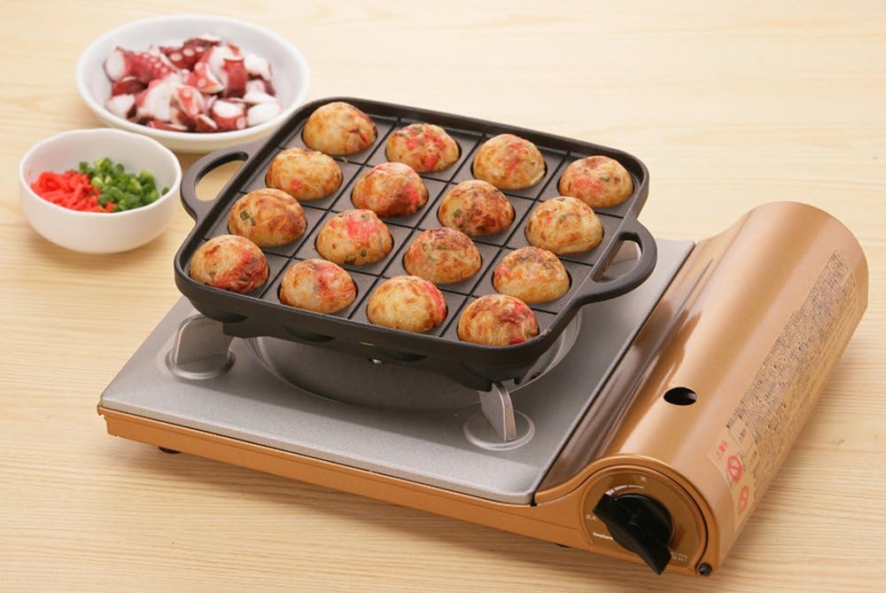 Finished browned takoyaki balls in the Iwatani grill pan over a butane stove