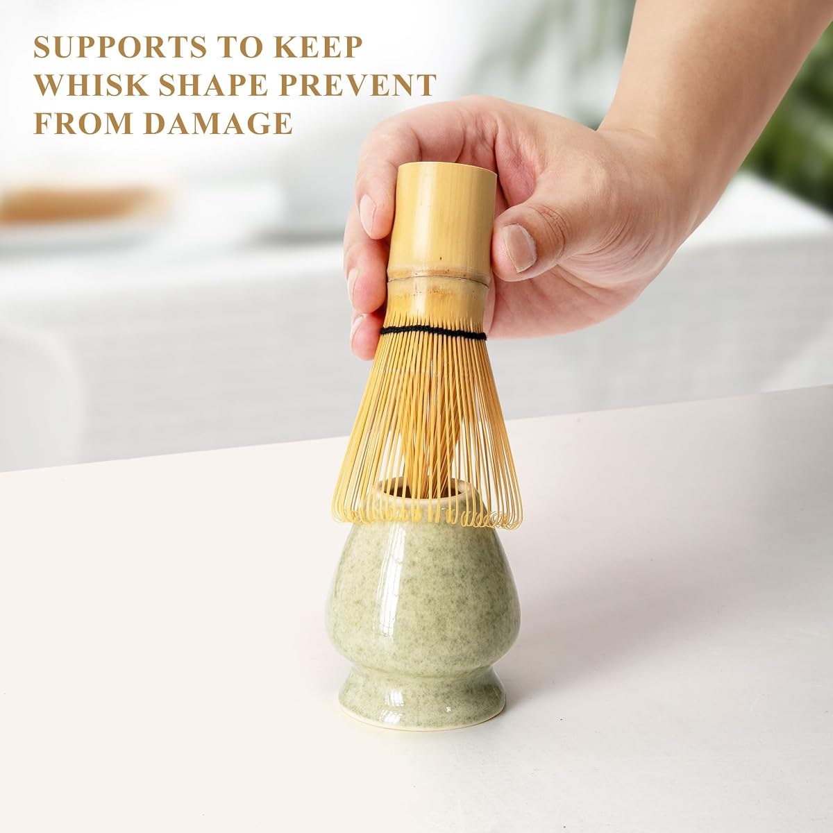 Hand lowering the YIBO bamboo whisk onto its green ceramic holder so the tines keep their shape