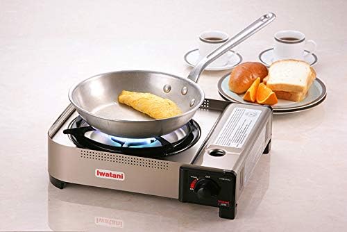 The Iwatani 35FW in use with a steel frying pan cooking an omelette next to bread and coffee
