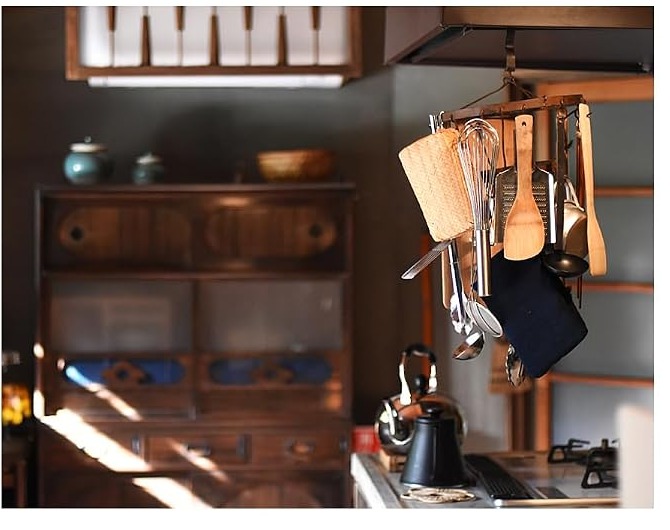 A Japanese home kitchen with utensils hanging from a rail above the stove