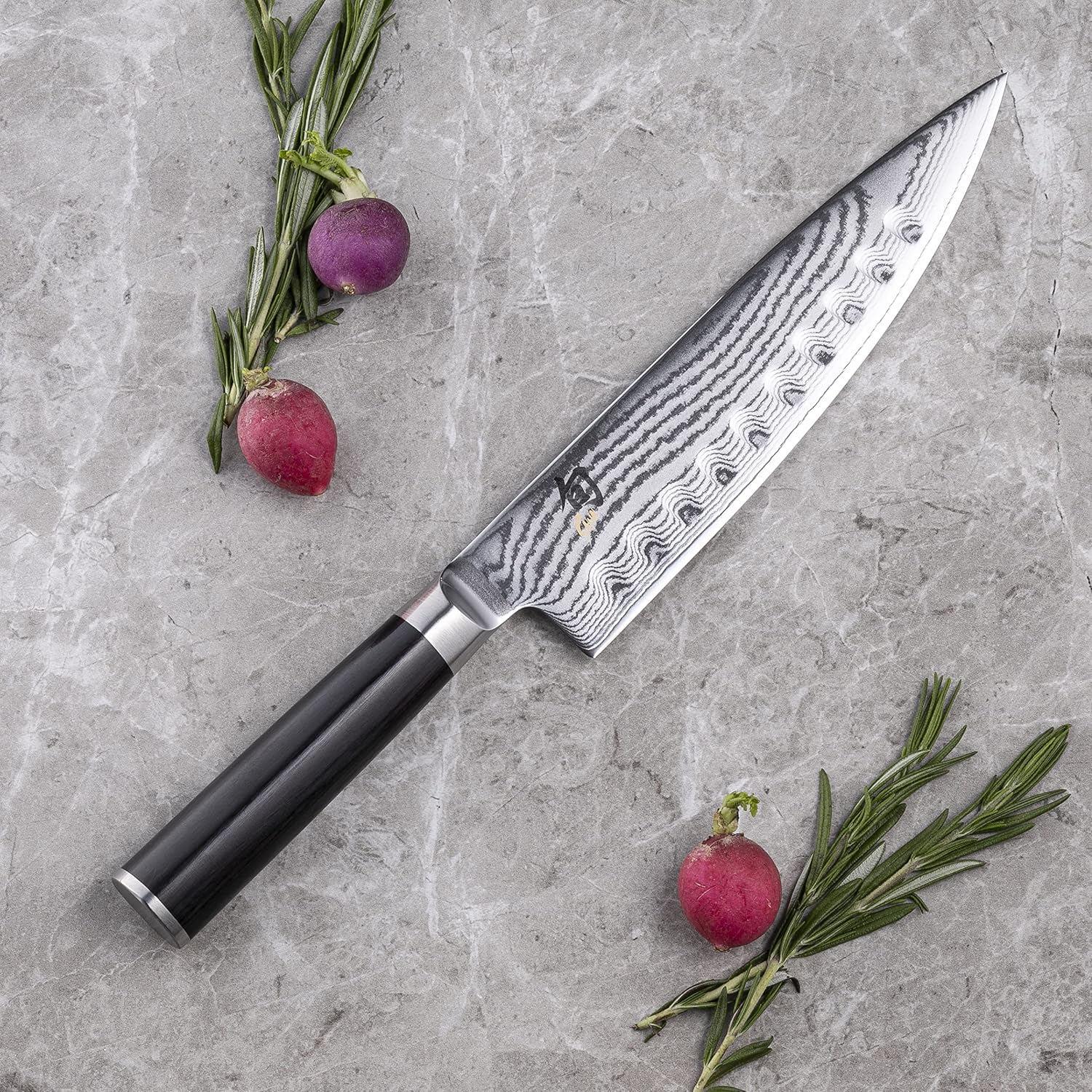 Shun Classic hollow-ground chef's knife on a marble counter beside radishes and rosemary