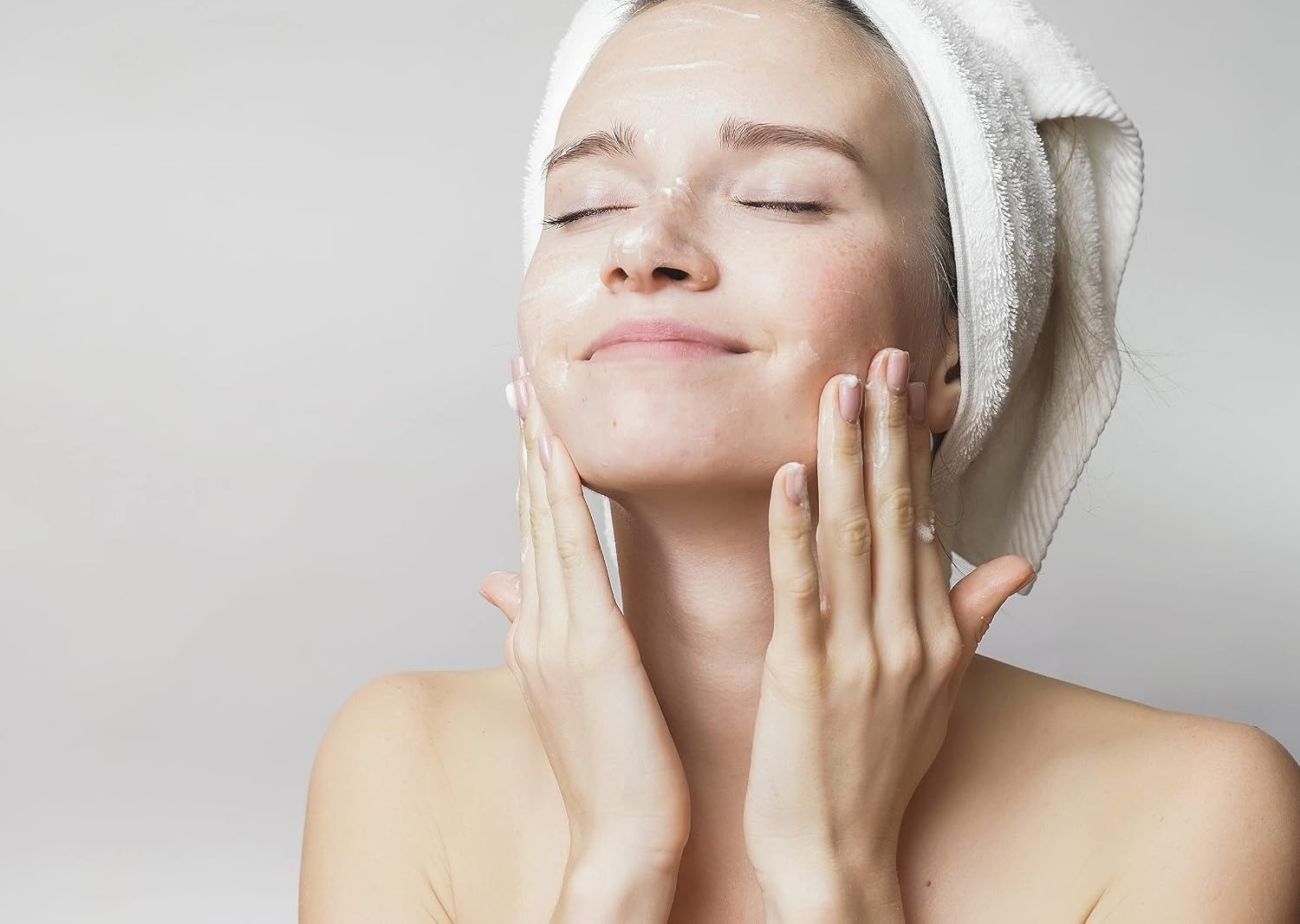 Woman pressing hydrating lotion into her cheeks after washing her face