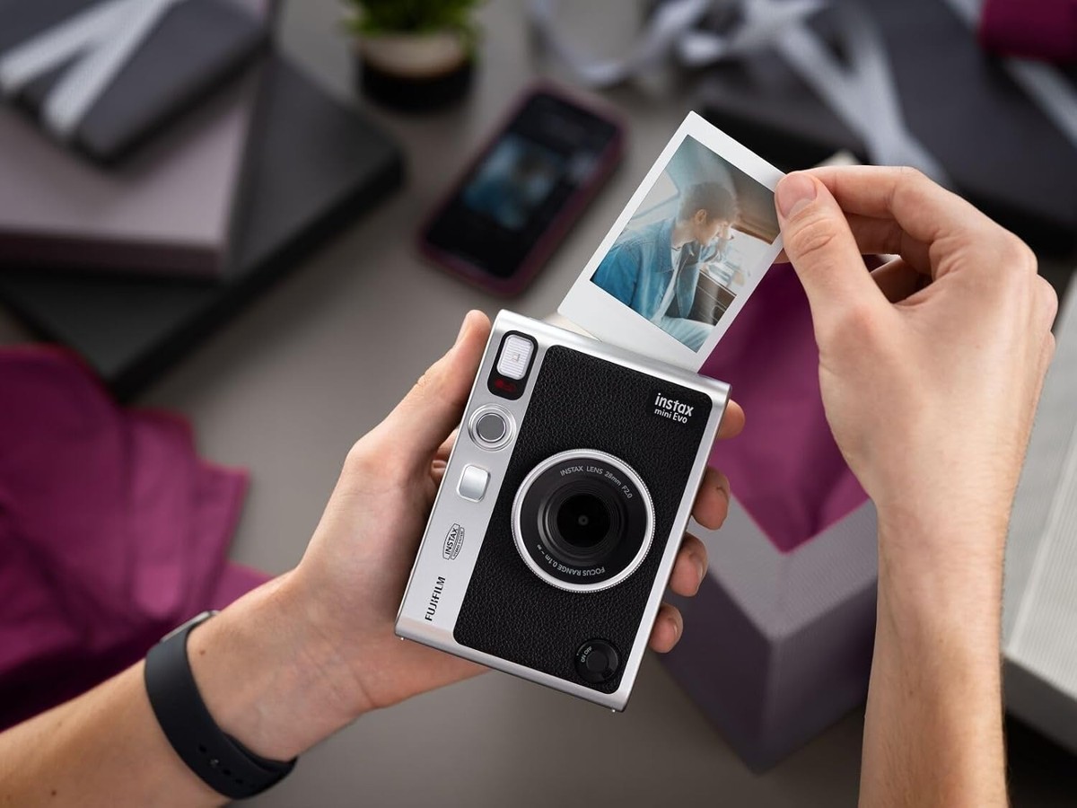 Hands holding the instax mini Evo with a fresh instax mini print
