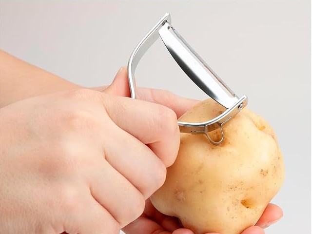 Kai Select 100 T-peeler side scoop used to remove an eye from a potato