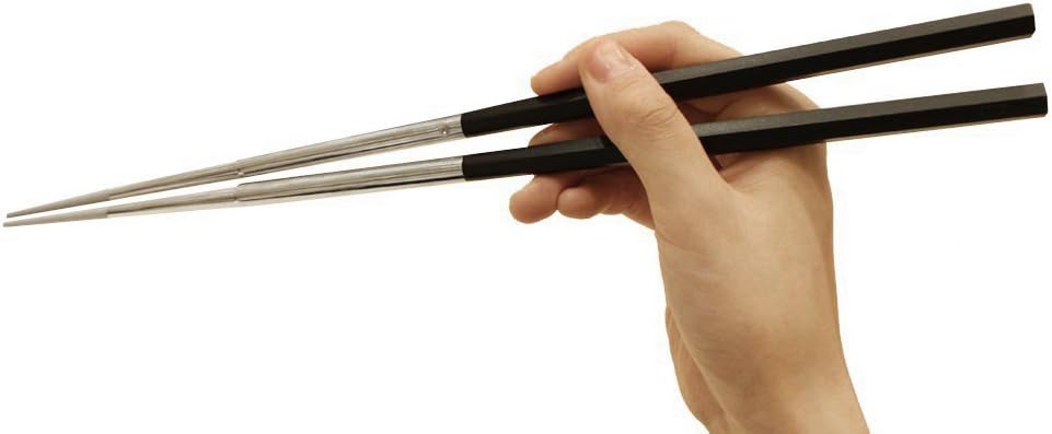 Kai SELECT100 stainless steel saibashi with black hexagonal handles held in a hand