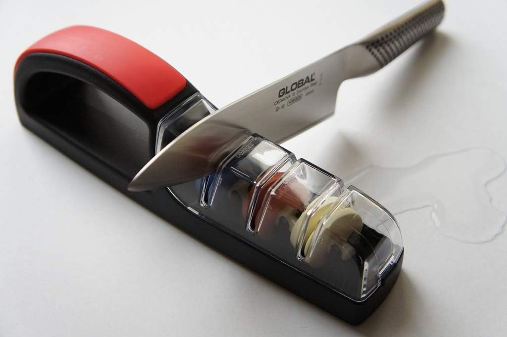 GLOBAL knife being drawn through the MinoSharp 3 water sharpener on a kitchen counter