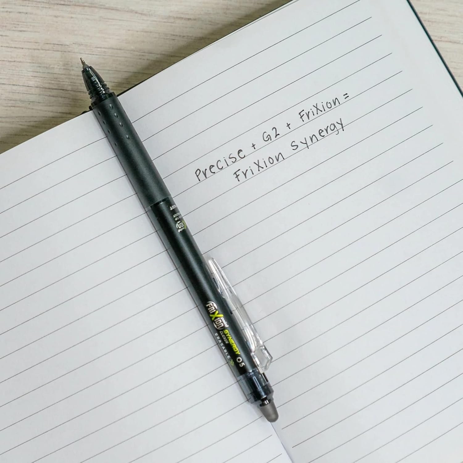 FriXion Synergy Clicker lying on an open lined notebook with handwriting