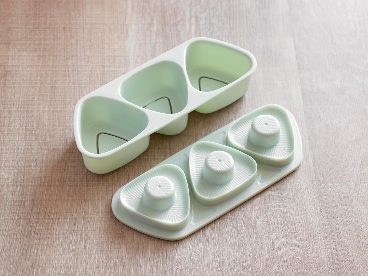 Skater three-cavity onigiri mold tray and lid in gray-green on a wooden table
