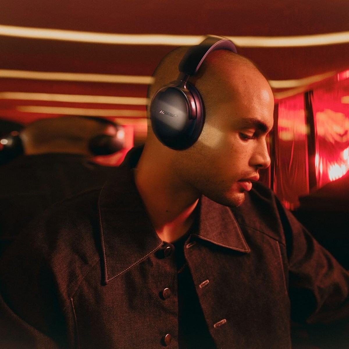 Man wearing Bose QuietComfort Ultra 2nd Gen headphones in a dim lounge