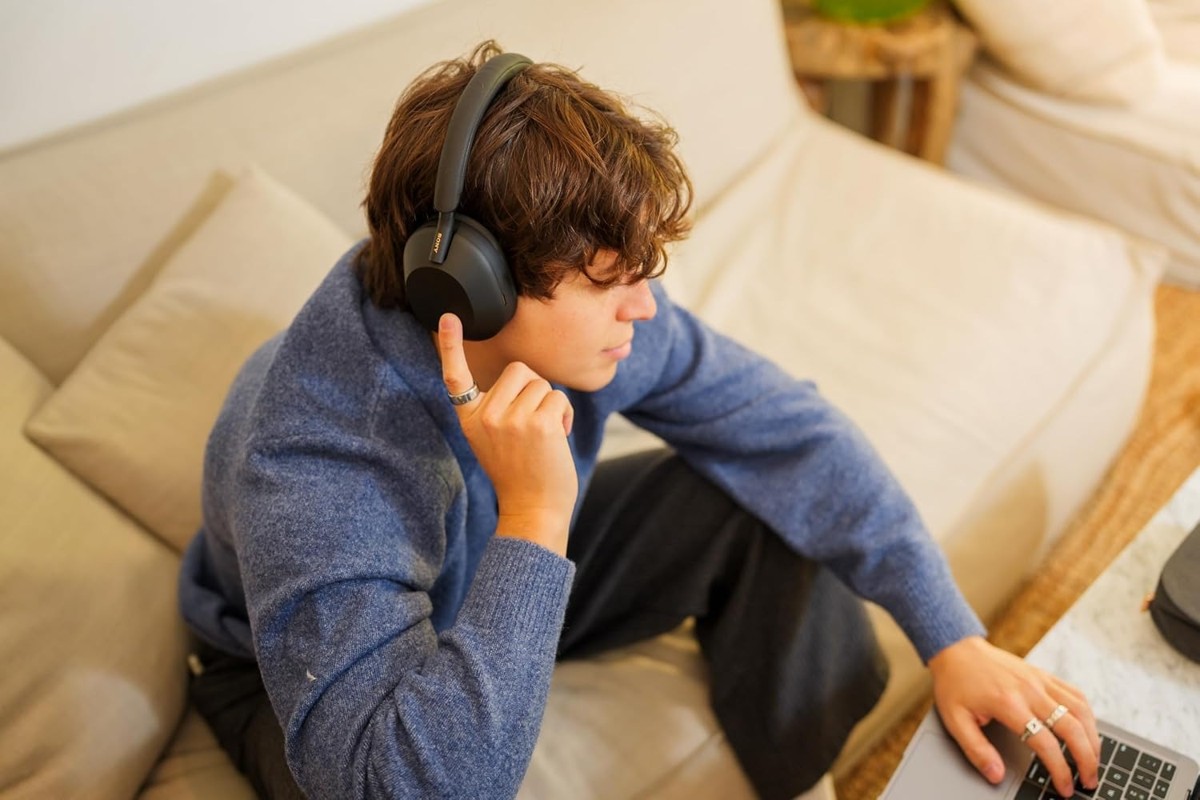 Person wearing Sony WH-1000XM5 while working on a laptop at home