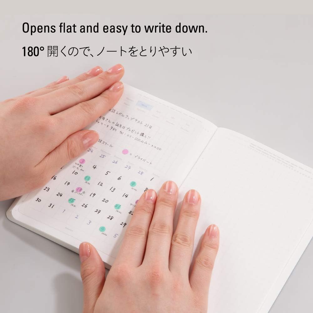 Hands writing in a Stalogy notebook opened flat on a desk
