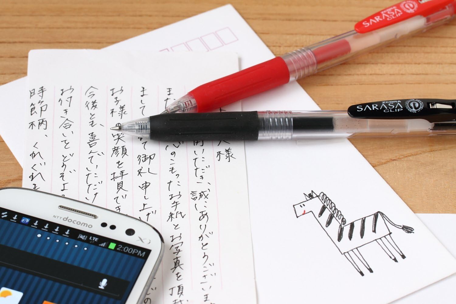 Zebra Sarasa Clip pens lying on handwritten notes and a sketch